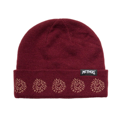 Maroon beanie with embroidered designs and a visible brand logo on a light gray background