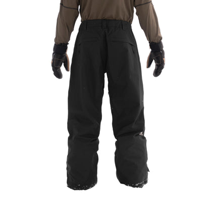 Person wearing black snow pants and gloves standing in the snow